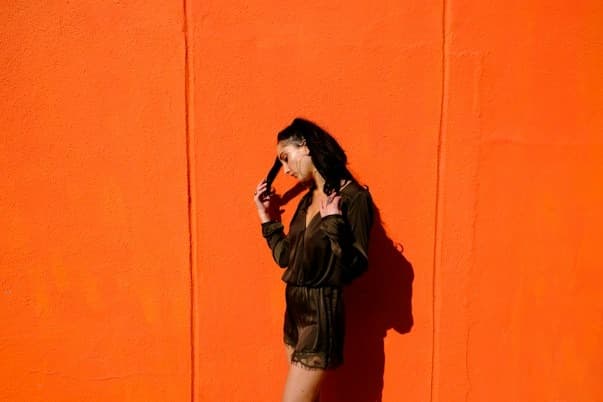 Art We Create - Fashion model against solid vibrant orange studio backdrop